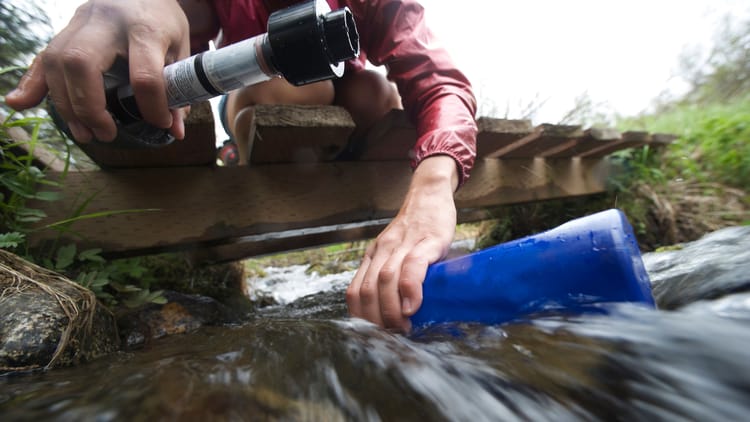 a female hiker filling up her water bottle to showcase portable water filter rv options